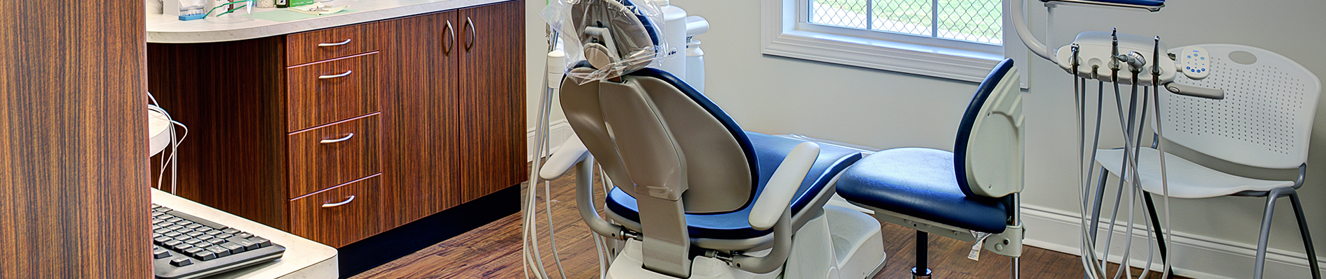 The image shows a modern dental clinic interior with various pieces of equipment, including a dental chair and an X-ray machine.